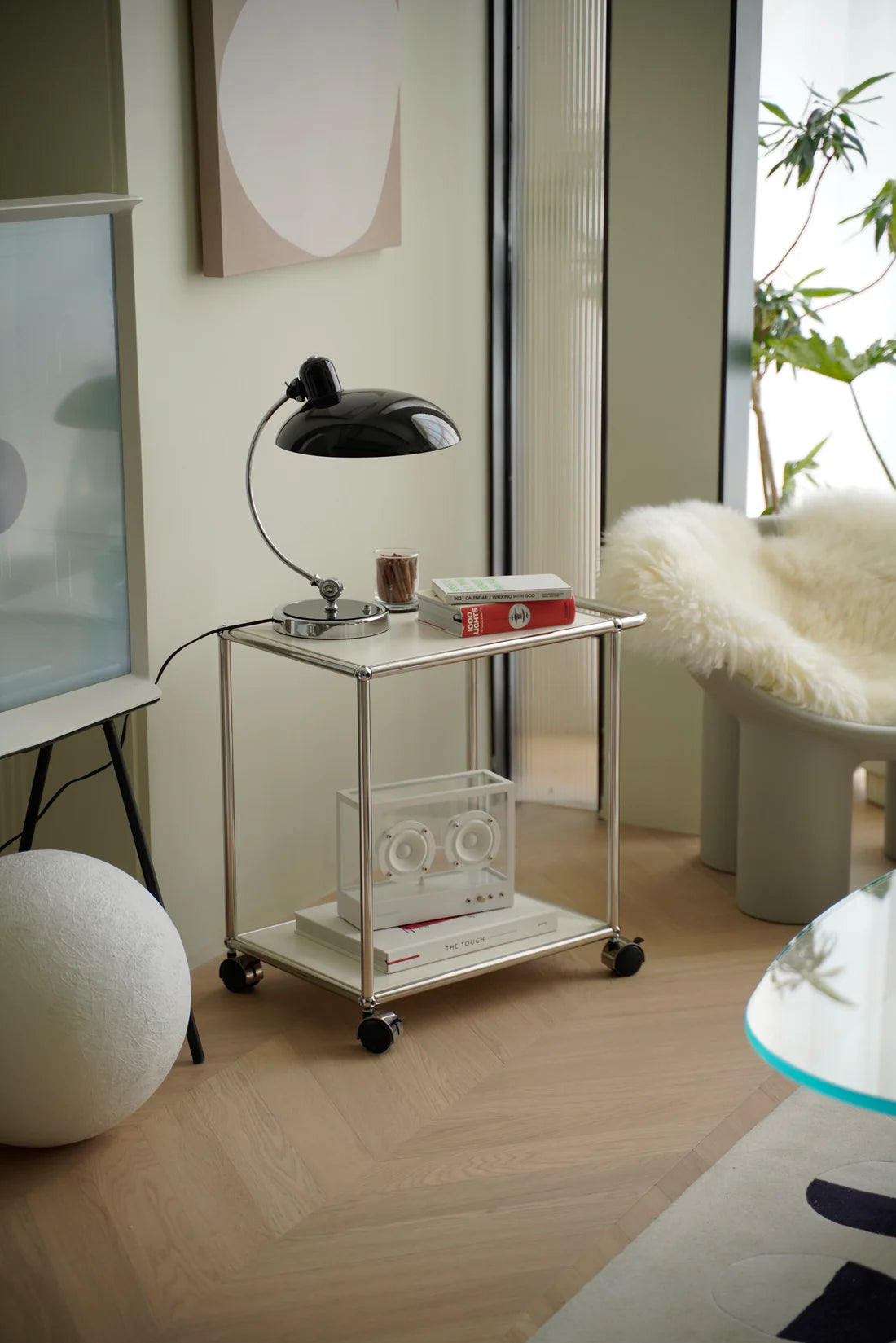 Small metal replica USM modular cart with a lamp and books in a modern room setting