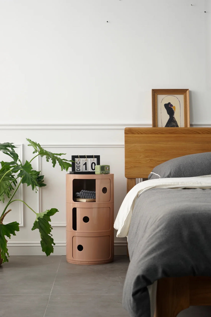 Bedroom with a pink nightstand plastic storage containers, bed, and plant