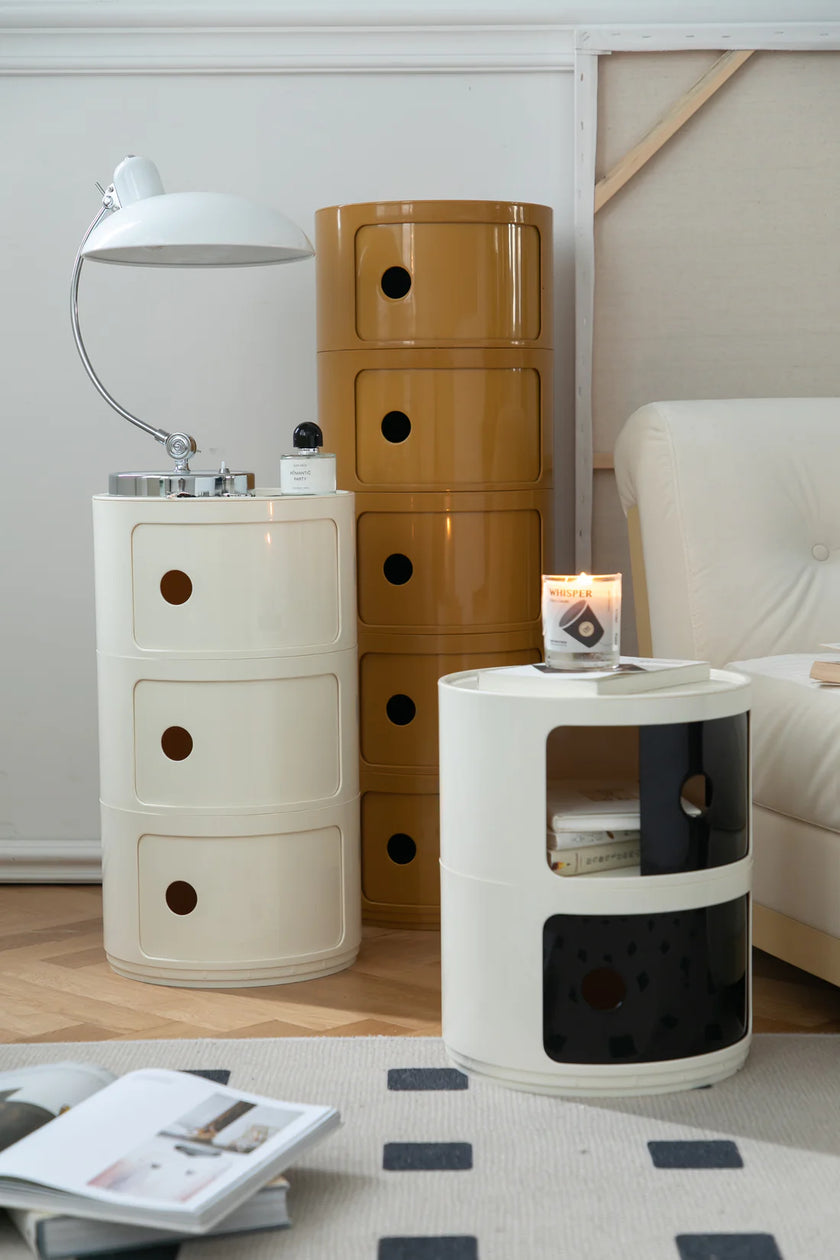 Three cylindrical storage units in a living room setting with a lamp and magazine.