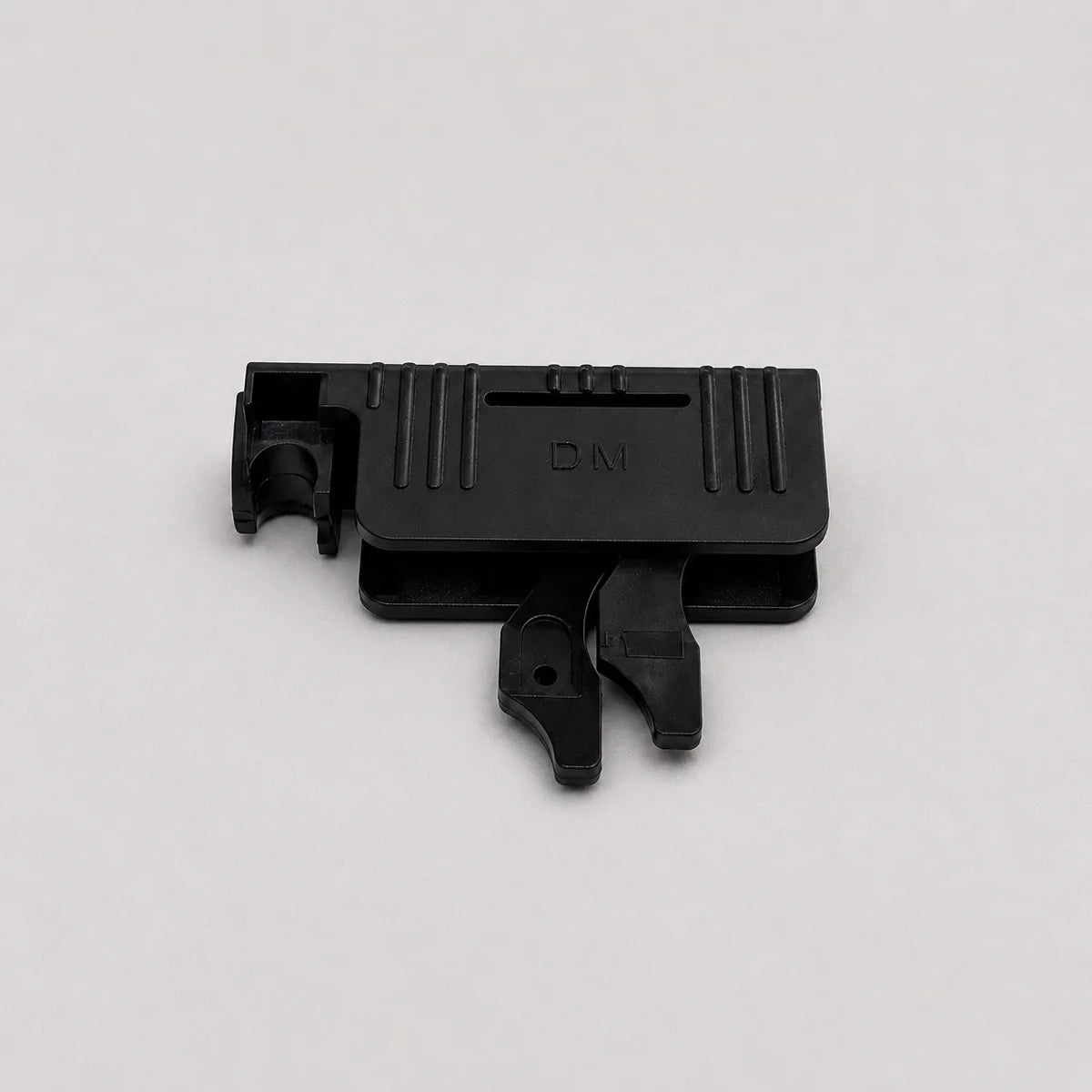 A small black plastic component with molded ridges and a tab-like protrusion, photographed on a plain light gray background.