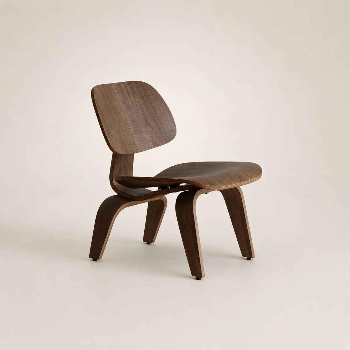 A mid-century modern wooden chair with a curved plywood seat and backrest, shown from a three-quarter angle on a light beige background.