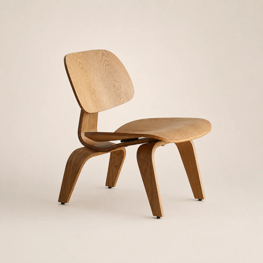 A mid-century modern wooden chair with a curved plywood seat, backrest, and legs, shown on a plain beige studio background.