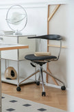 Modern desk lounge chair with a black seat and backrest in a minimalistic office setting.