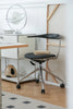 Modern desk lounge chair with a black seat and backrest in a minimalistic office setting.