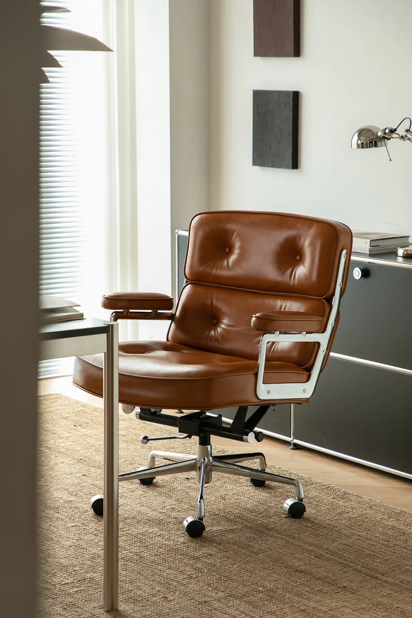 Brown leather office chair in a modern office setting with a desk and window.