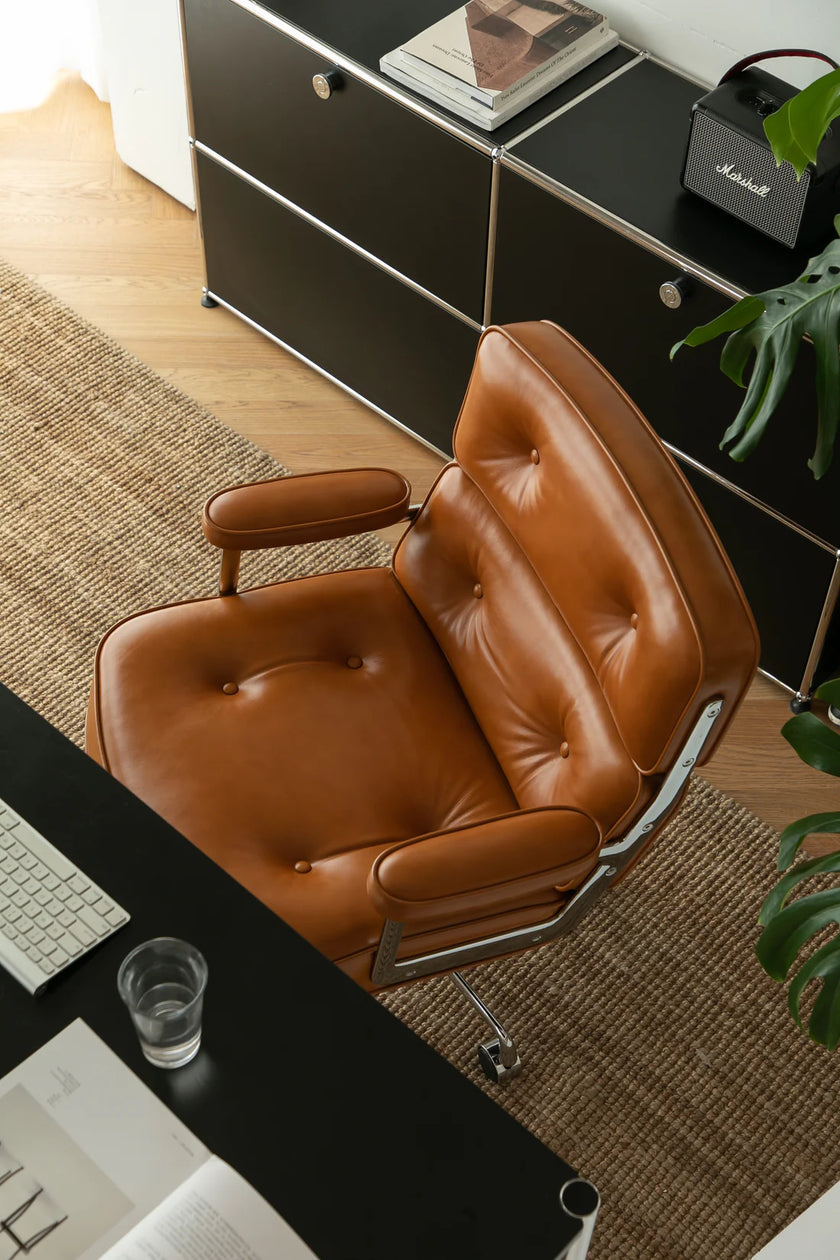 Brown leather office chair in a modern office setting with a desk and computer.