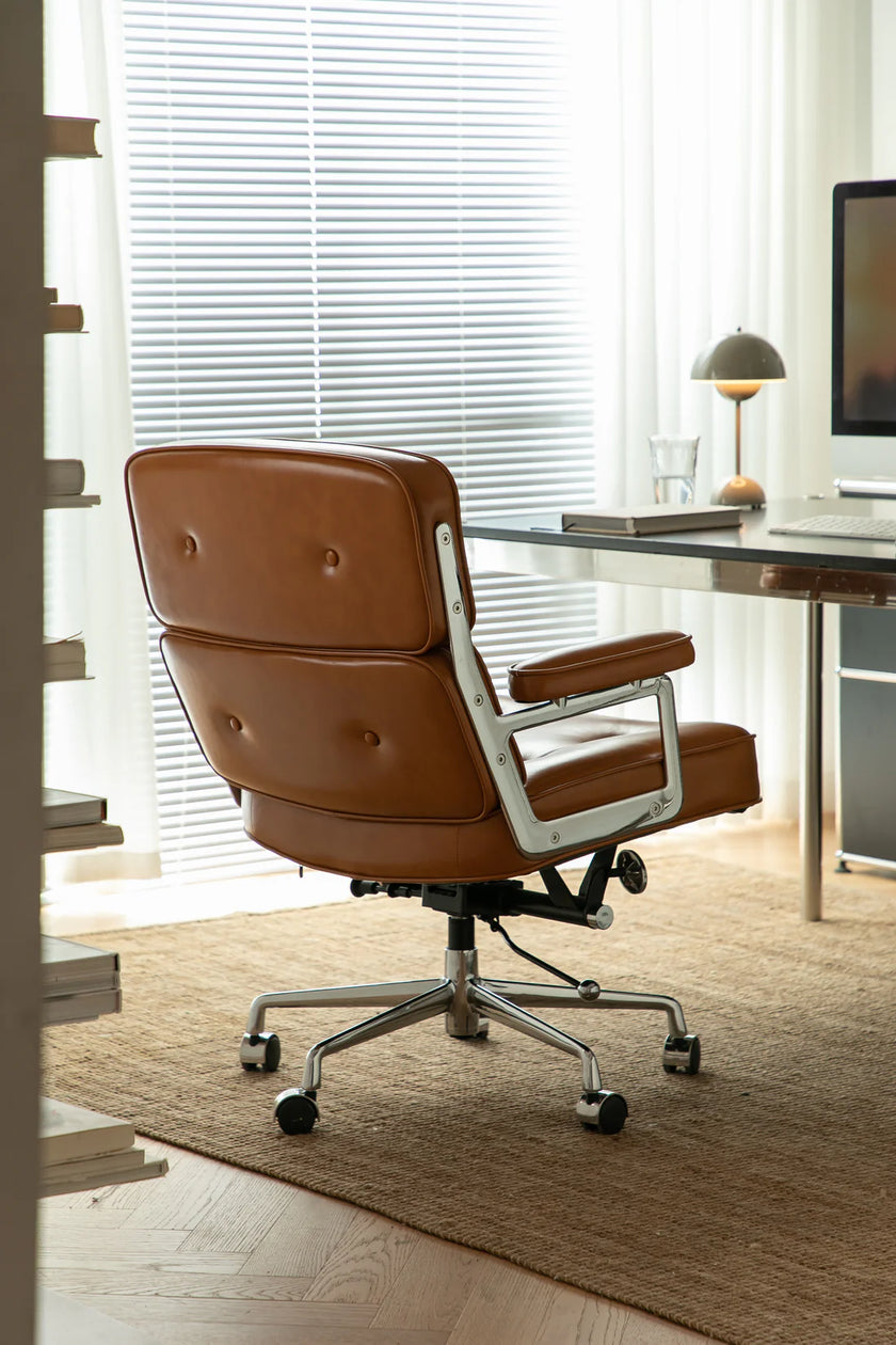 Brown office computer chair in a modern office setting with a desk and computer monitor.