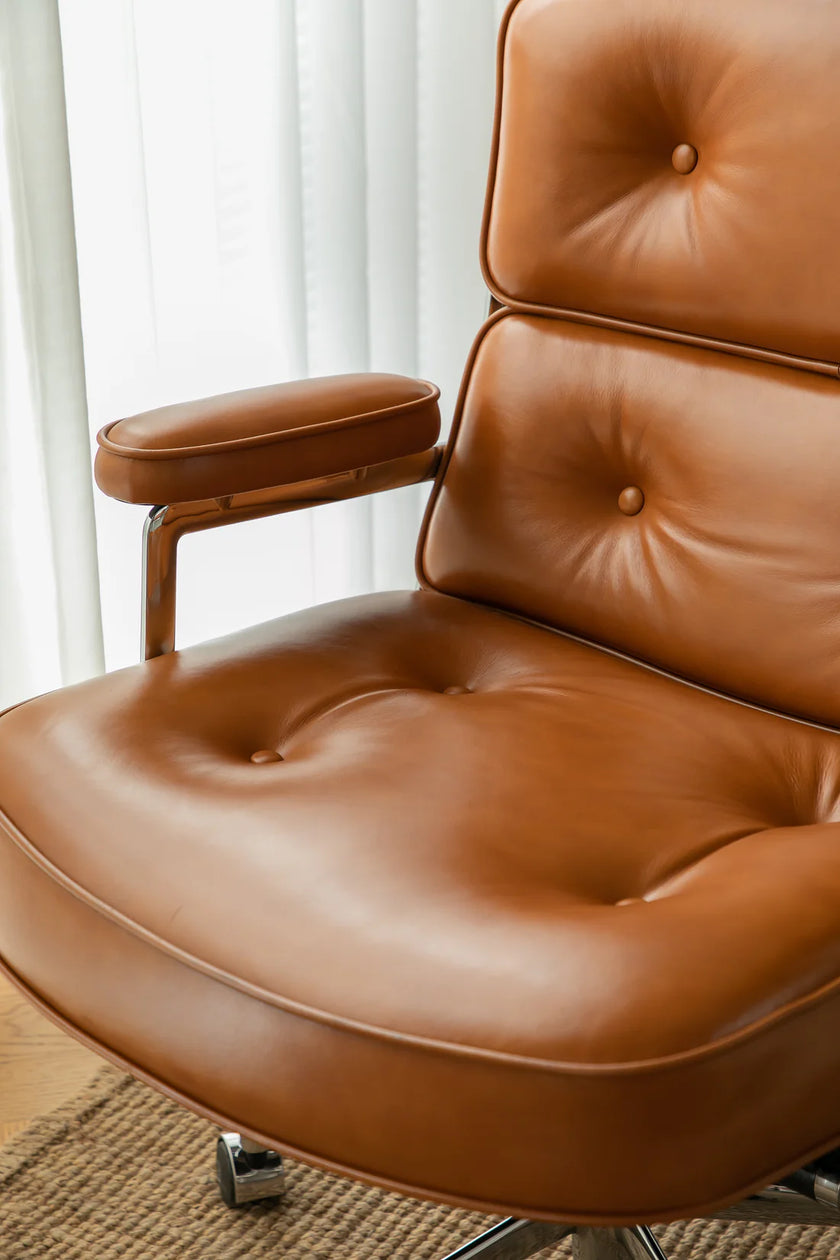 Brown leather office arm chair with armrests in a room with white curtains.