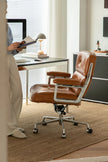 Brown office swivel chair in a modern office setting with a desk and computer.