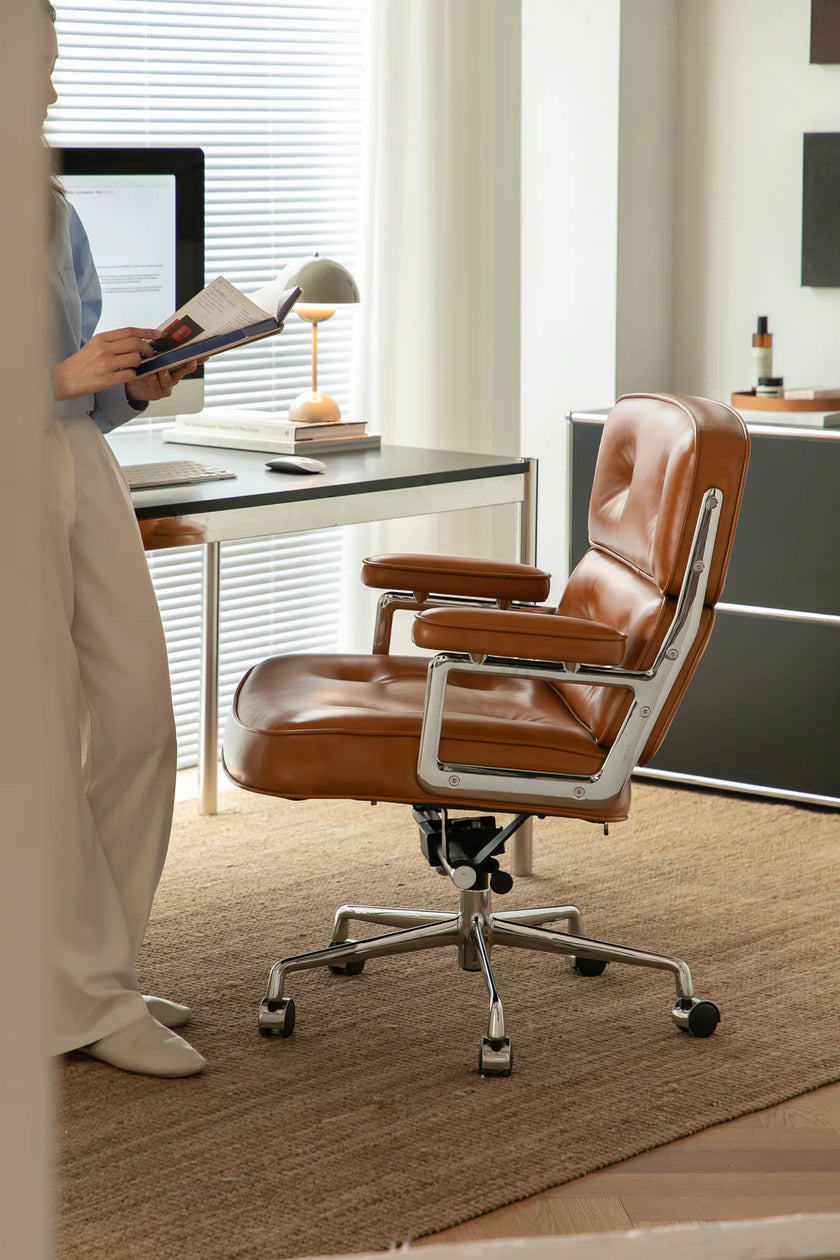 Brown office swivel chair in a modern office setting with a desk and computer.