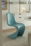 A modern light blue molded plastic chair, resembling the iconic Palladio Mole design, positioned in a minimalist, contemporary room with white furniture and a textured rug.