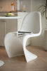 Modern white plastic dining room chair with a magazine on a wooden floor in a minimalistic room.