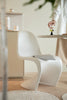 Modern white plastic chair with a person holding a glass of water in a minimalistic room.
