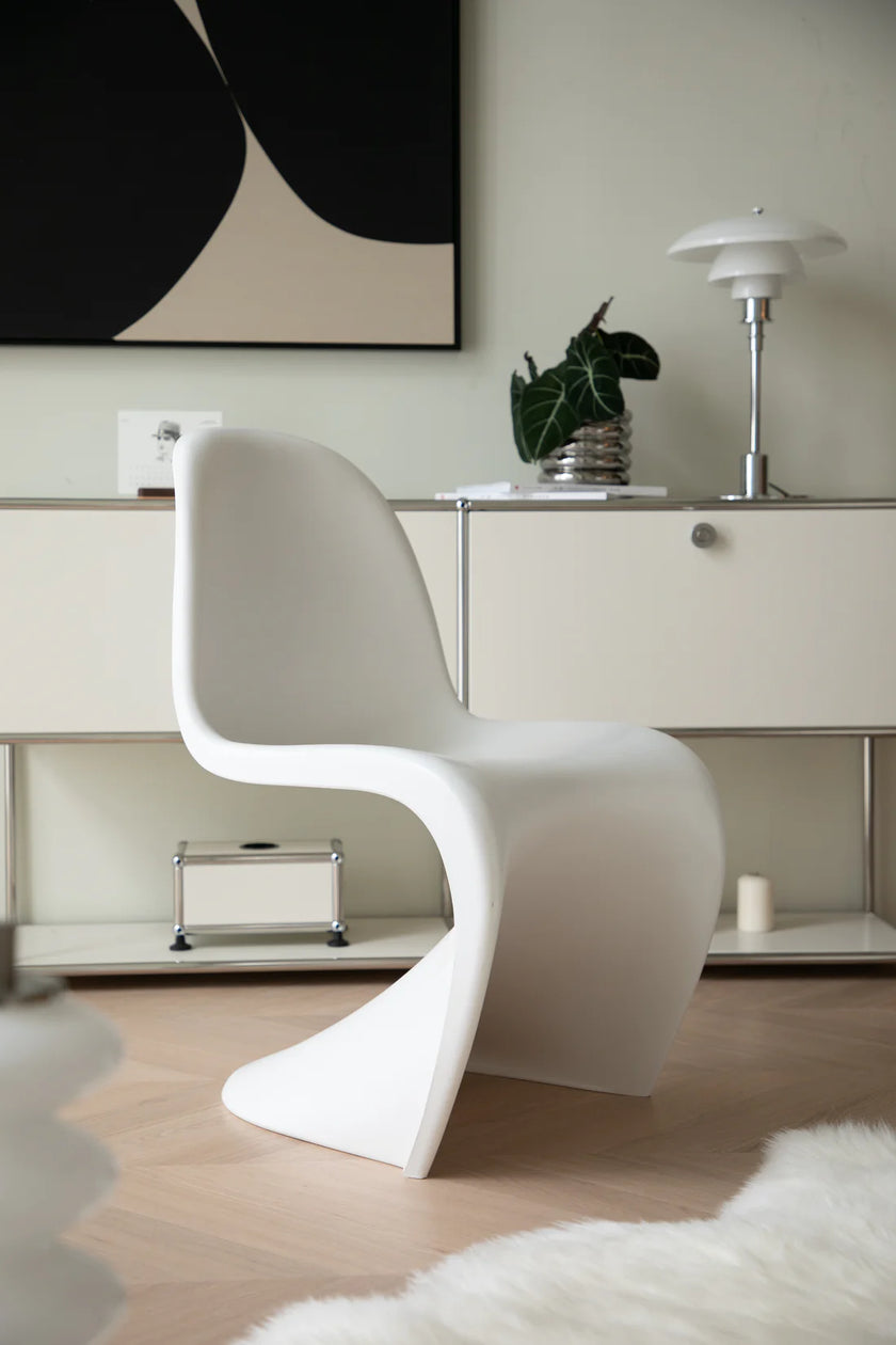 Modern white living room chair in a stylish room with a painting and lamp.