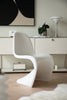 Modern white living room chair in a stylish room with a painting and lamp.