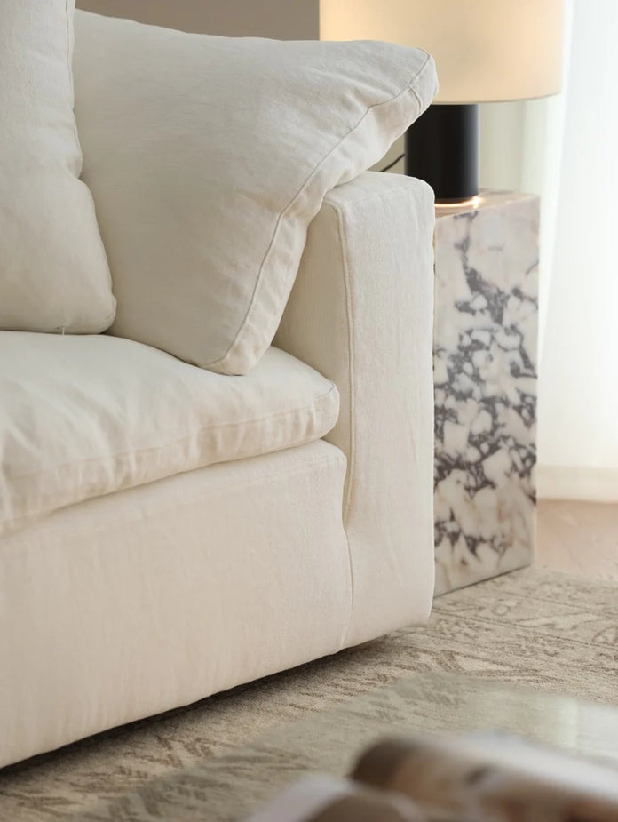 Beige sofa with a lamp and decorative item in the background