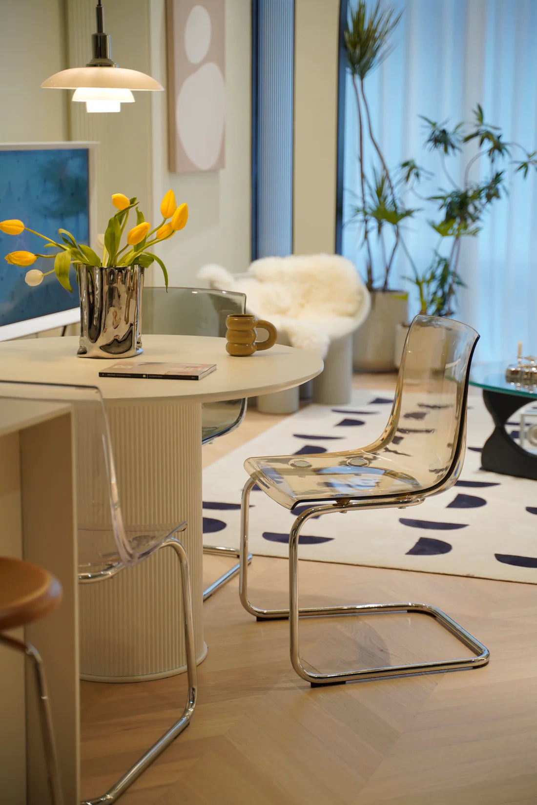 Modern living room with a round table, dining room chairs, and decorative elements.