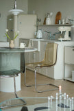 Modern kitchen with white cabinets, a glass table, and transparent dining room  chairs.
