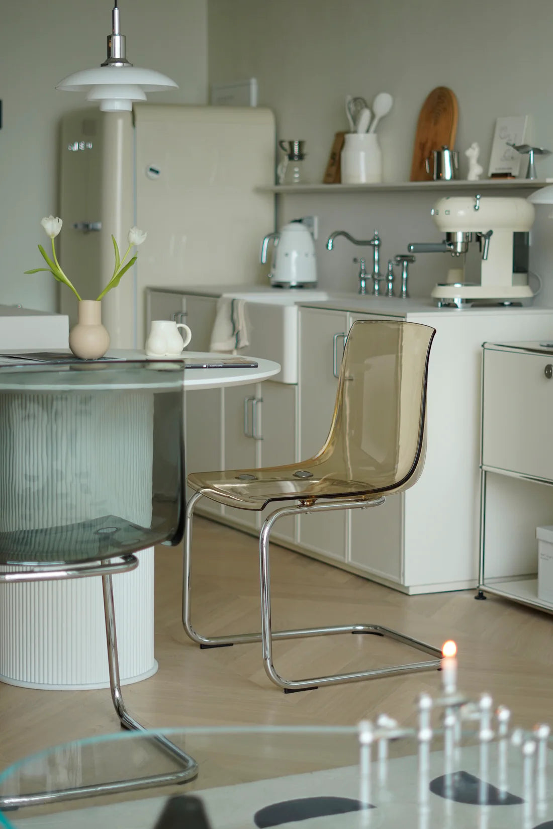 Modern kitchen with white cabinets, a glass table, and transparent dining room  chairs.