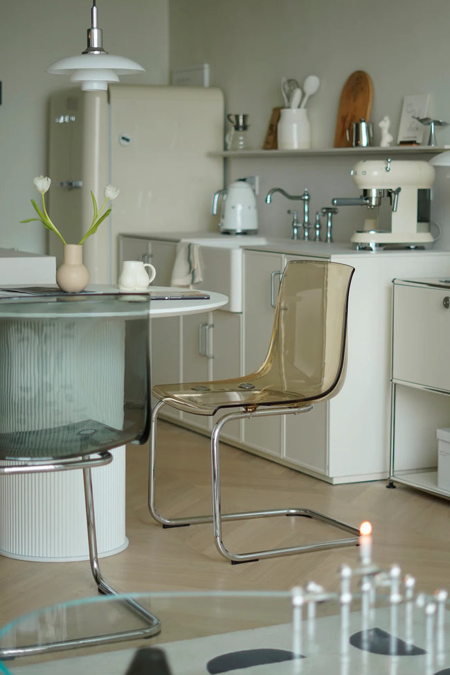 Modern kitchen with white cabinets, a glass table, and transparent dining room  chairs.