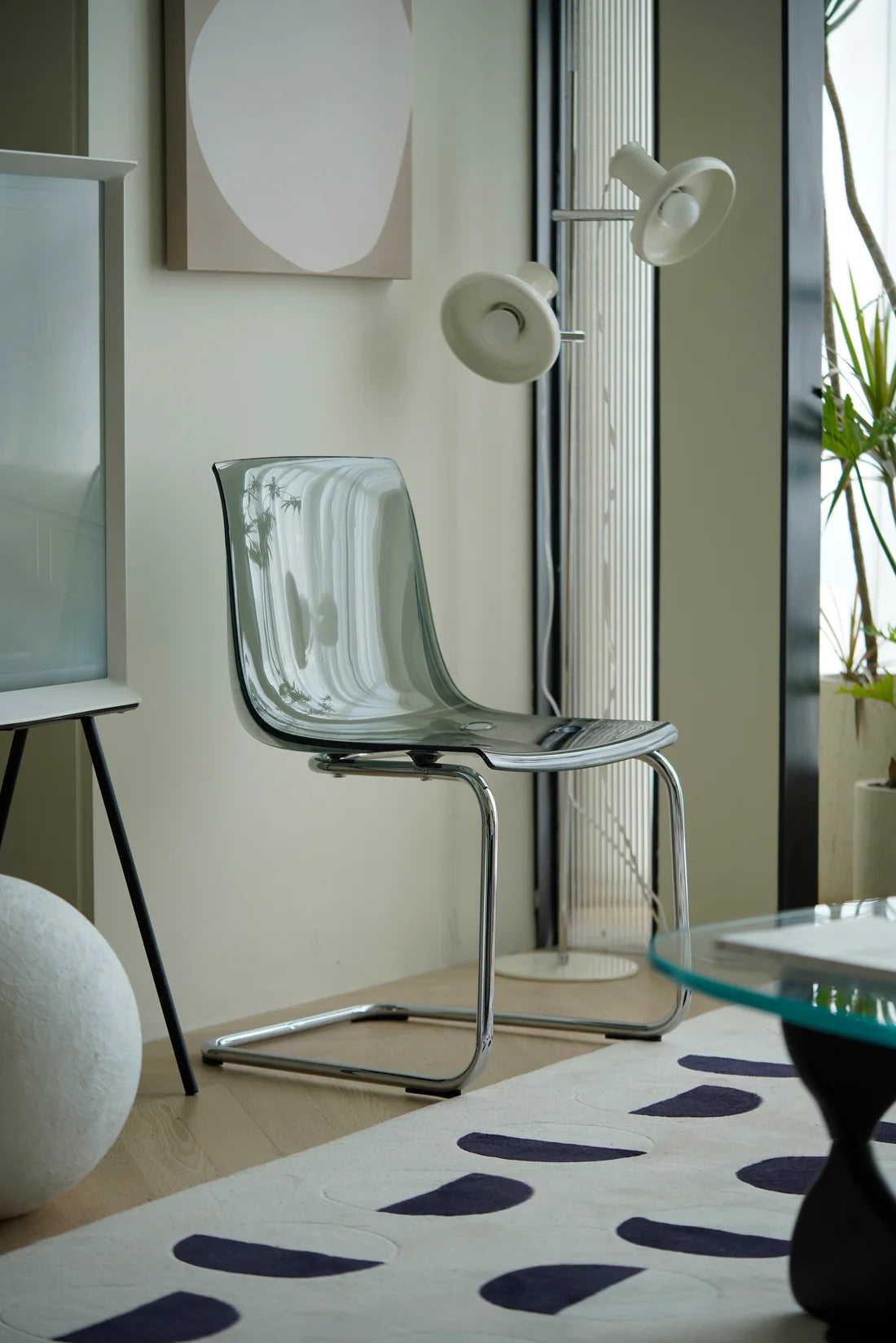 Modern plastic dining room chair in a room with a glass table and decorative elements.