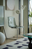 Modern plastic dining room chair in a room with a glass table and decorative elements.