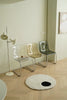 Modern interior with transparent plastic chairs, a floor lamp, and a round rug on wooden flooring.