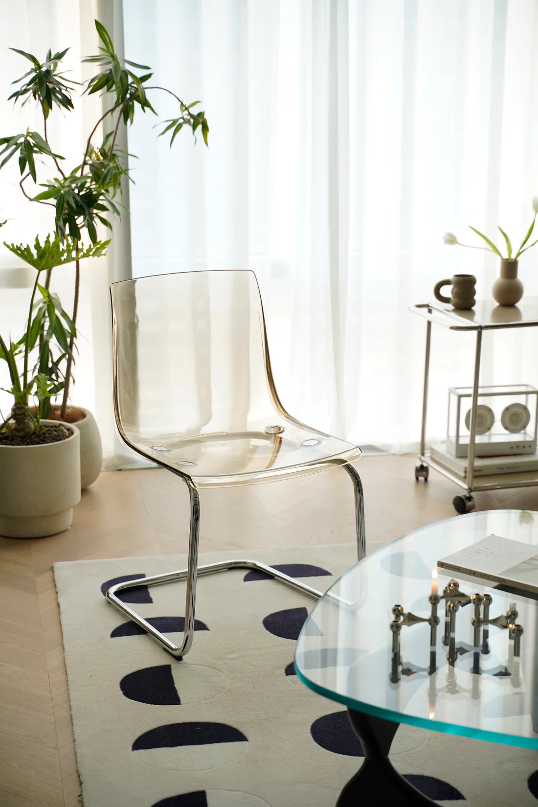 Modern living room with transparent living room chair, glass table, and decorative elements.