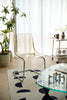 Modern living room with transparent living room chair, glass table, and decorative elements.