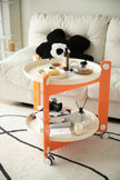 Orange and white sofa side table with drinks and snacks on a living room floor.