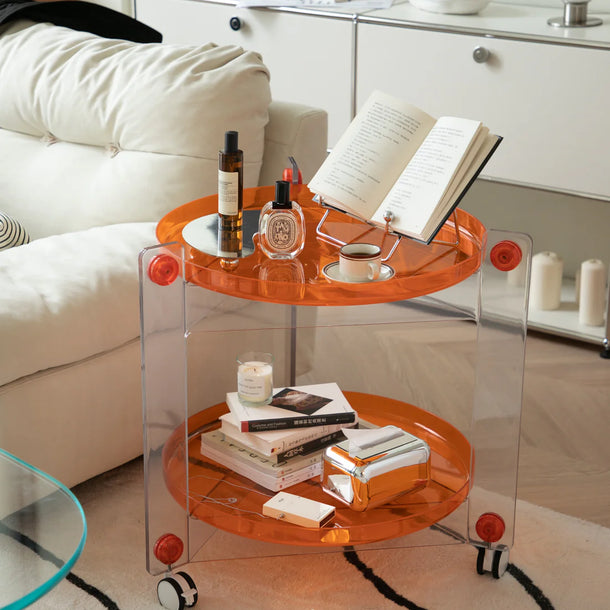 Modern living room with a transparent round side table on wheels, books, and bottles.