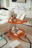Modern living room with a transparent round side table on wheels, books, and bottles.