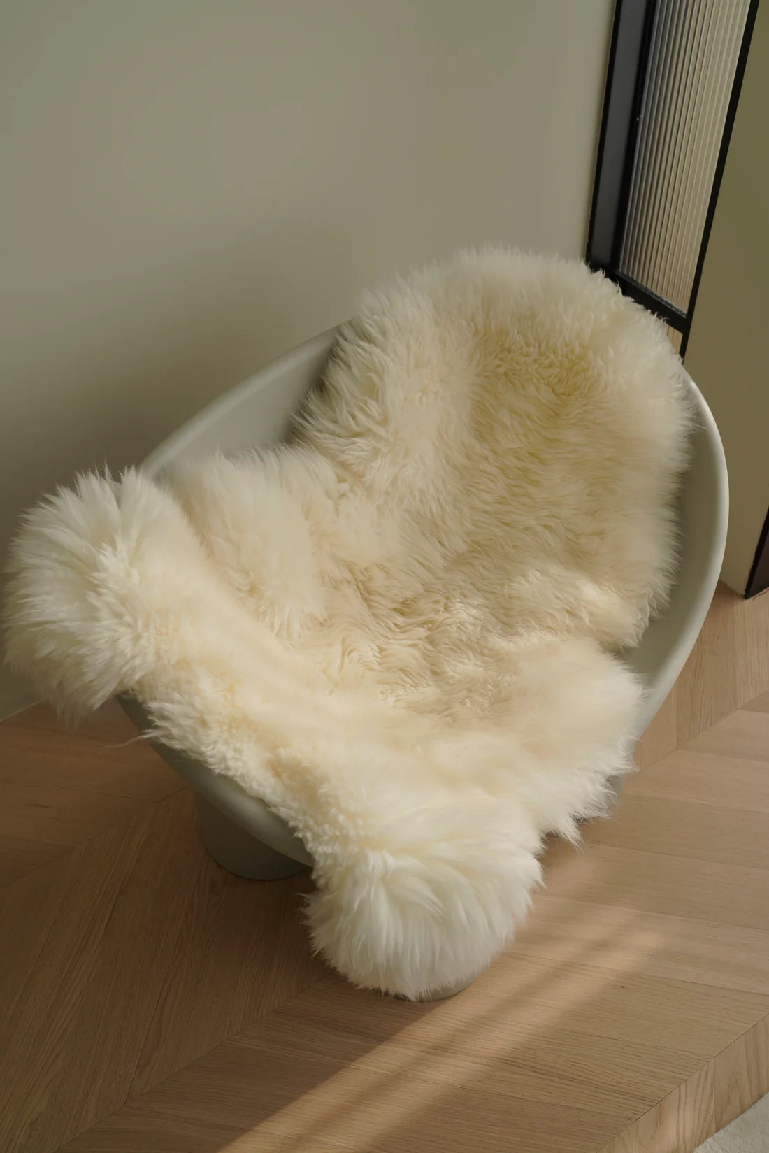 White wool fabric chair cushions on a chair against a neutral wall.