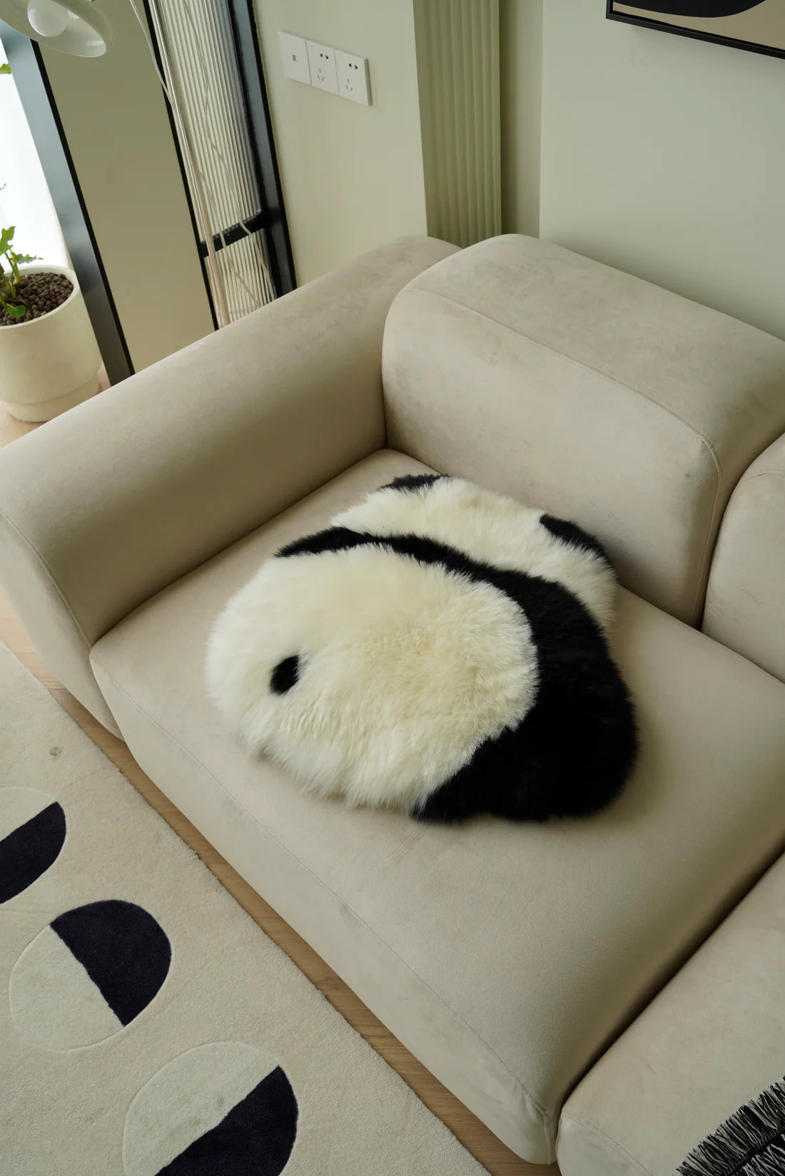 Panda-shaped pillow on a beige sofa in a living room setting