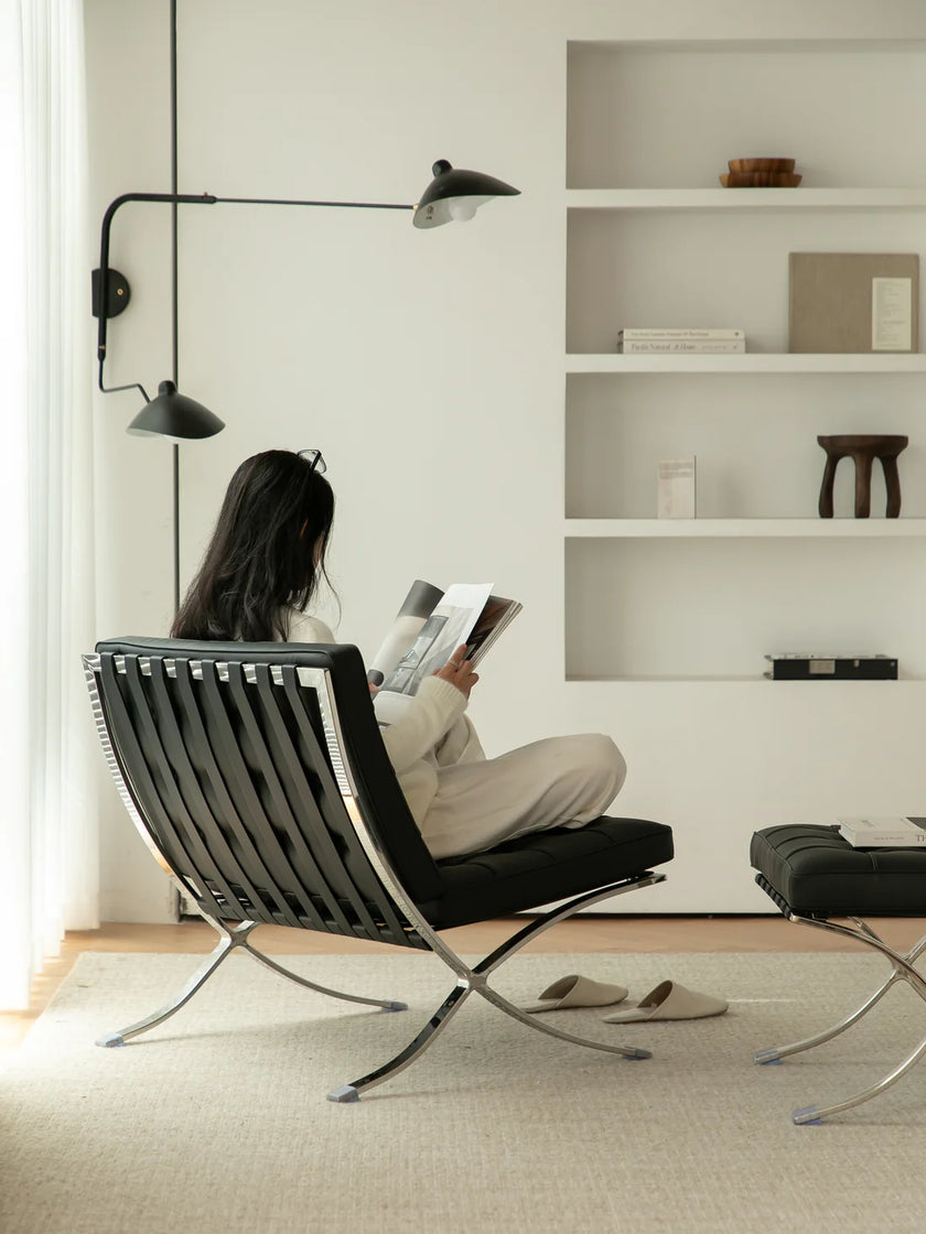 Lady sitting on a modern black recliner chair reading a book in a minimalistic living room.