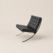 Modern black leather chair with chrome frame on a beige background