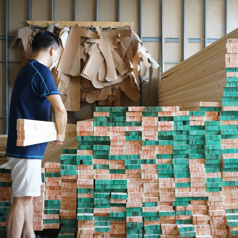 Person in a warehouse with stacks of green and brown bricks.