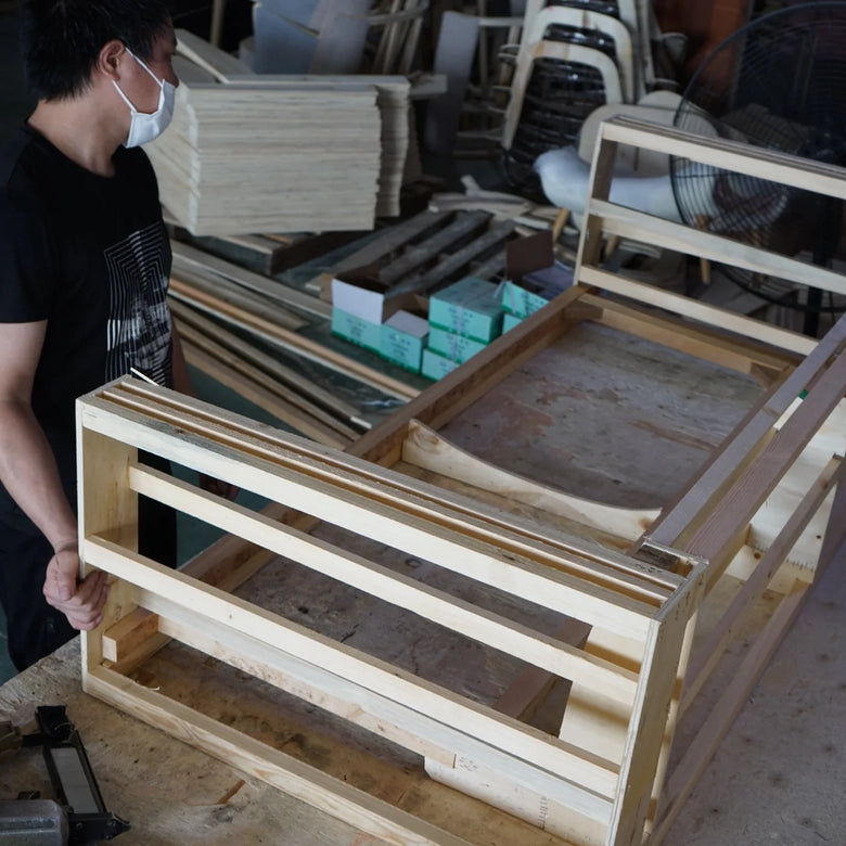 Person working on a wooden frame in a workshop setting