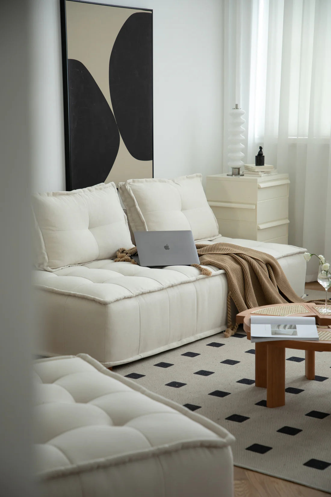 Modern living room with a white love seat sofa, coffee table, and abstract art on the wall.