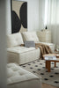Modern living room with a white love seat sofa, coffee table, and abstract art on the wall.