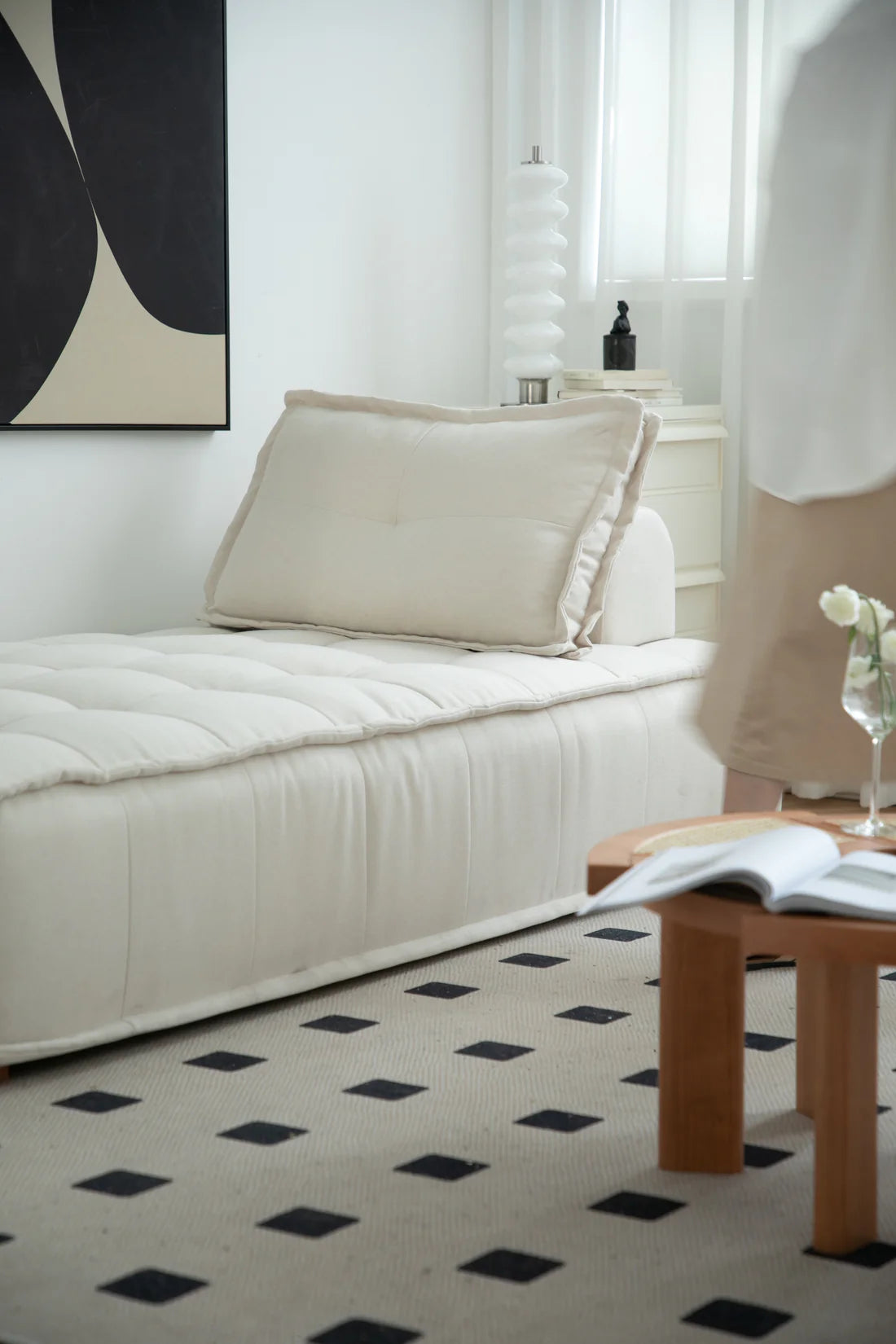 Modern living room with a white sofa, black and white patterned rug, and a small wooden table.