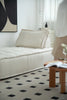 Modern living room with a white sofa, black and white patterned rug, and a small wooden table.