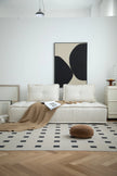 Modern living room with a white love seat sofa, abstract art, and geometric rug.