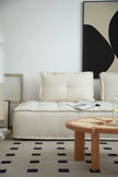 Modern living room with a white love seat sectional sofa, wooden coffee table, and abstract art on the wall.