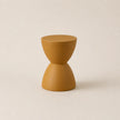 Mustard yellow hourglass-shaped stool on a beige background