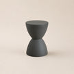 Dark gray hourglass-shaped stool on a beige background