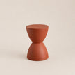 Terracotta-colored hourglass-shaped stool on a beige background