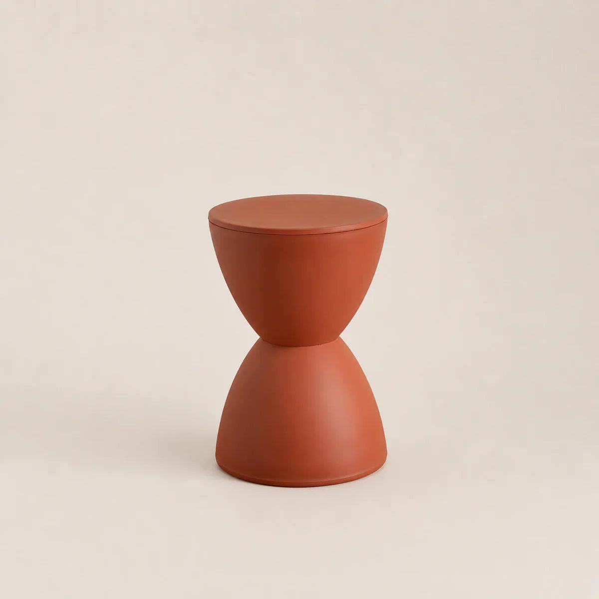 Terracotta-colored hourglass-shaped stool on a beige background