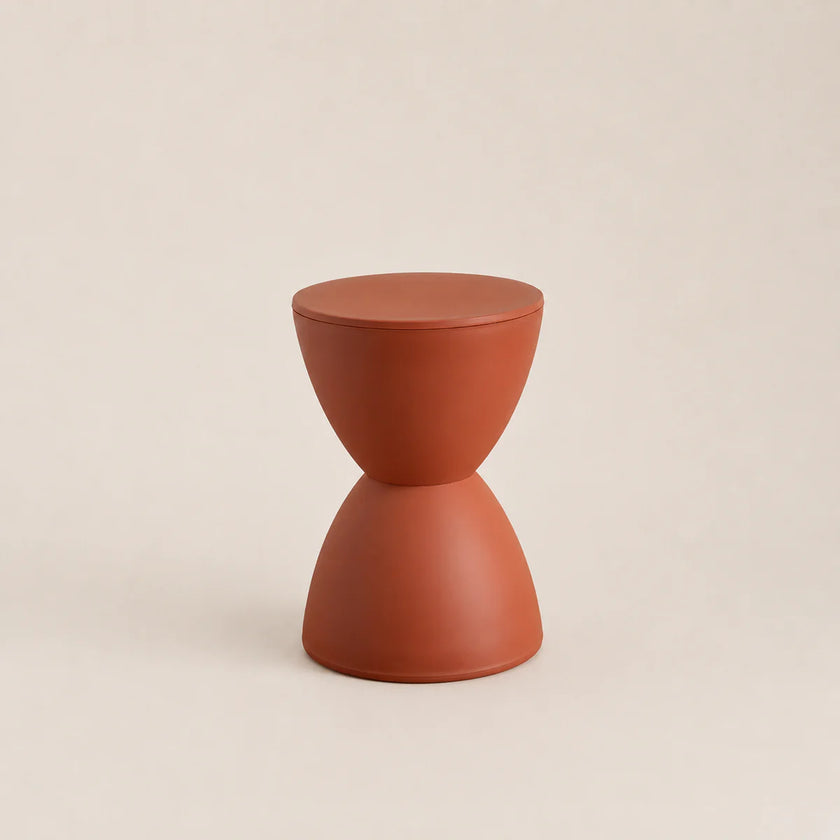 Terracotta-colored hourglass-shaped stool on a beige background