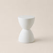 White ceramic hourglass-shaped object on a beige background